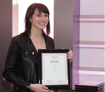 Smiling woman with black hair is holding an award