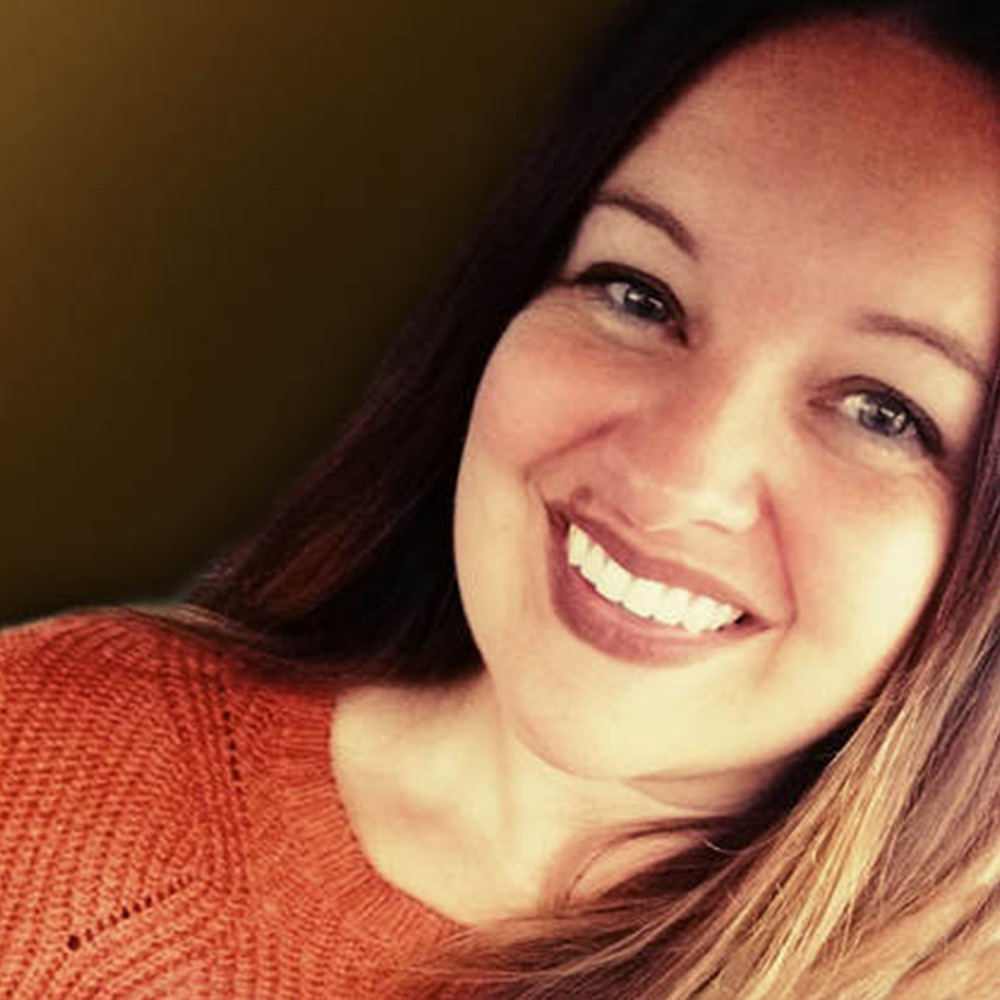 Selfie of woman with brown hair wearing an orange shirt