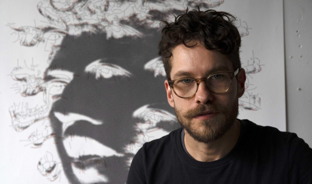 portrait of a man with short dark hair wearing glasses and a black shirt