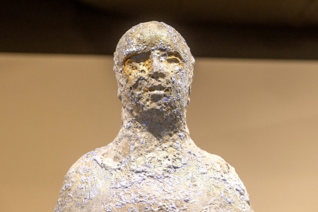 Ceramic textured sculpture of a human figure. The photo shows the head and shoulder of this figure. 