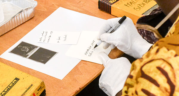 Person with white gloves carefully labeling and organizing photographs