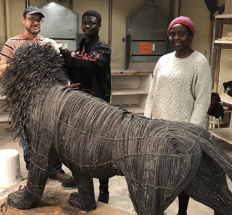 three people standing around a large sculpture of a lion
