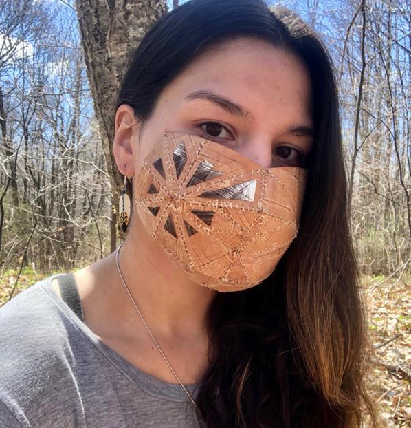 a woman with long dark hair wearing a grey shirt and a homemade mask