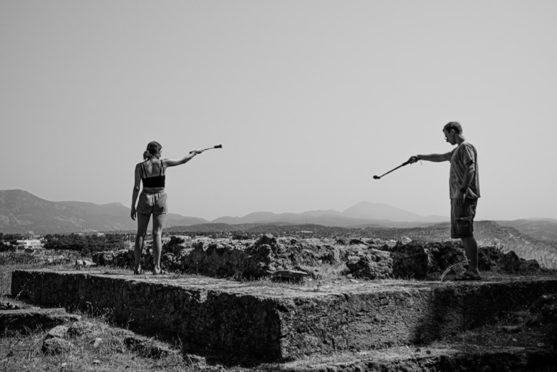 Two people standing on an excavation site using video cameras to capture the footage.