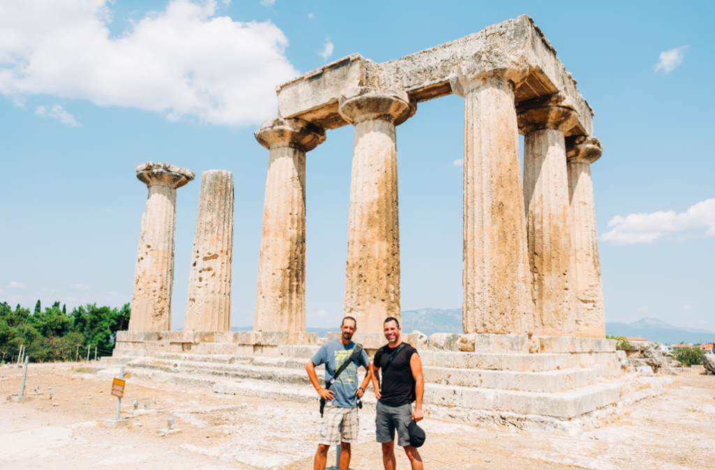 Two men standing side by side in front of ancient ruins.