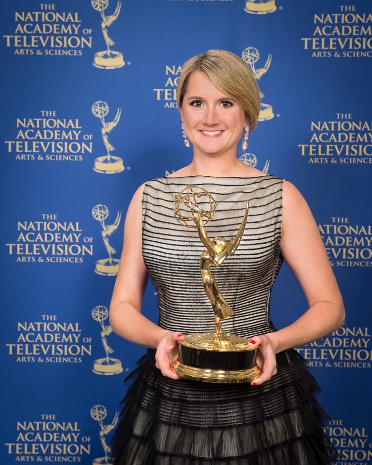Woman with blonde hair holding an Emmy award