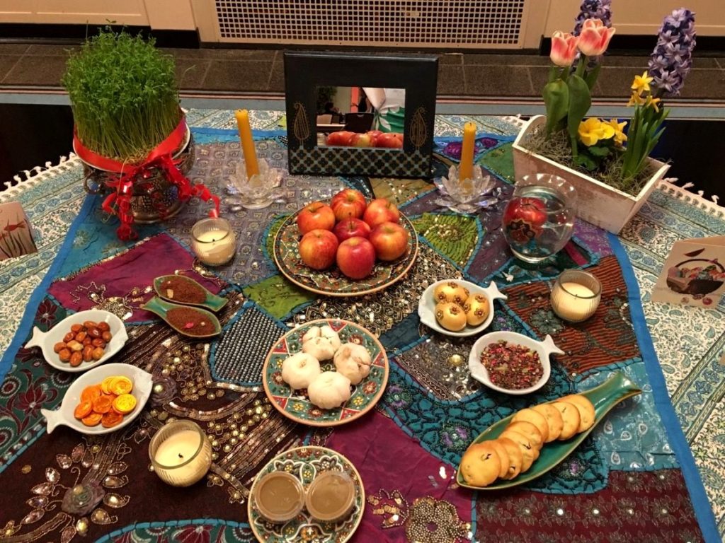 Flowers, decorated eggs, candles and food offerings on fish-shaped plates sit on top of colorfully patterned tablecloths. 