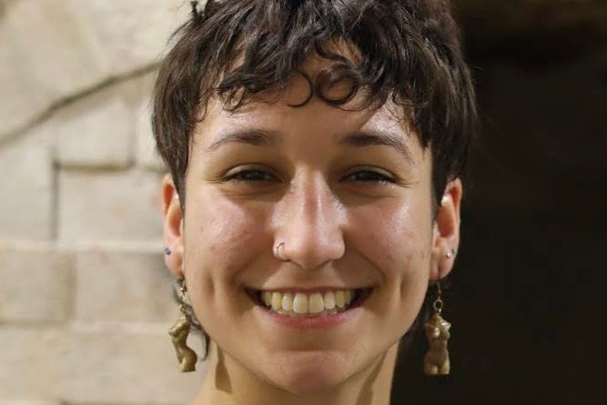 Headshot of a woman with short brown heair, long earrings, and smiling.