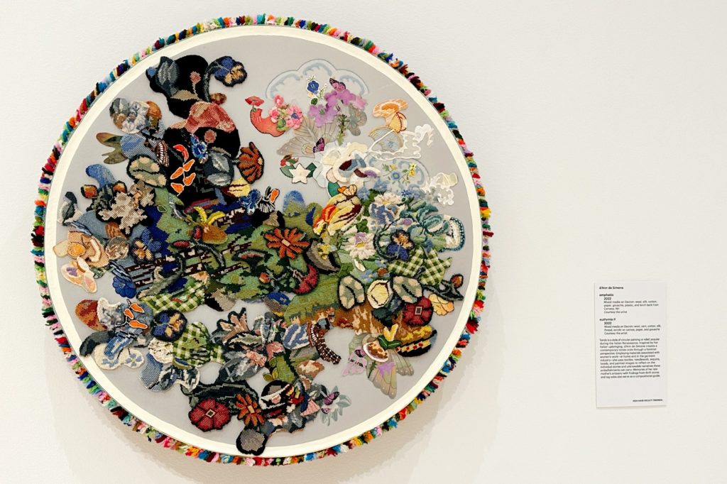 A picture of a circular, colorful piece of art hanging on a tan wall.