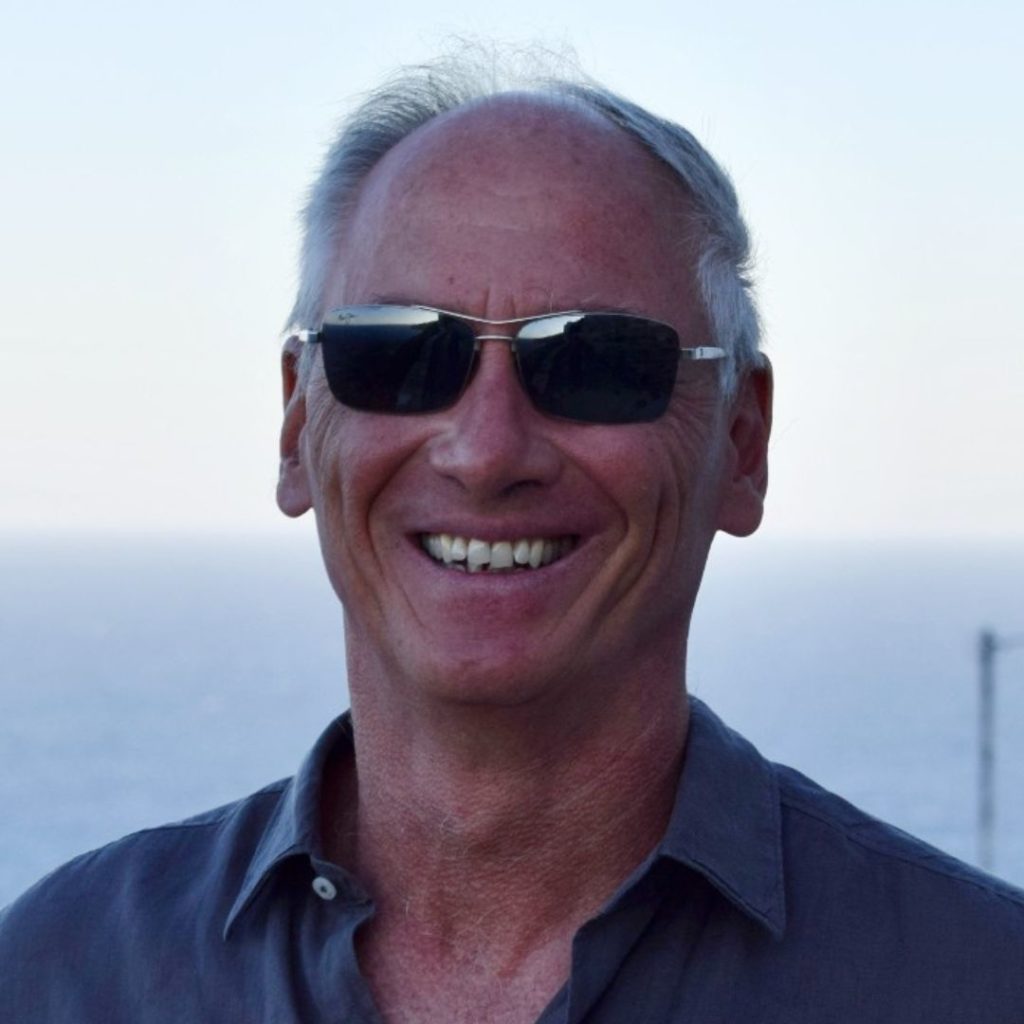 Portrait of a smiling man in sunglasses wearing a blue button-down.