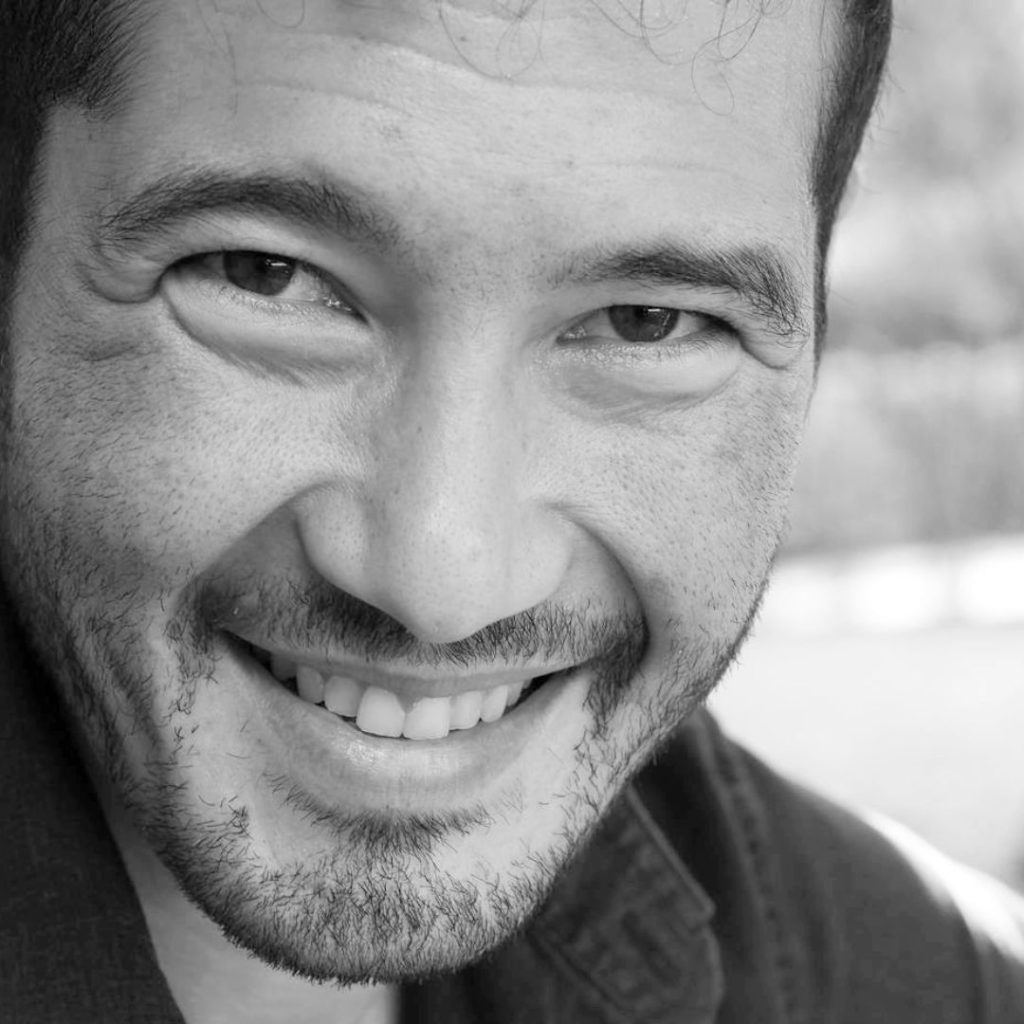 Black-and-white portrait of a smiling man in a button-down.