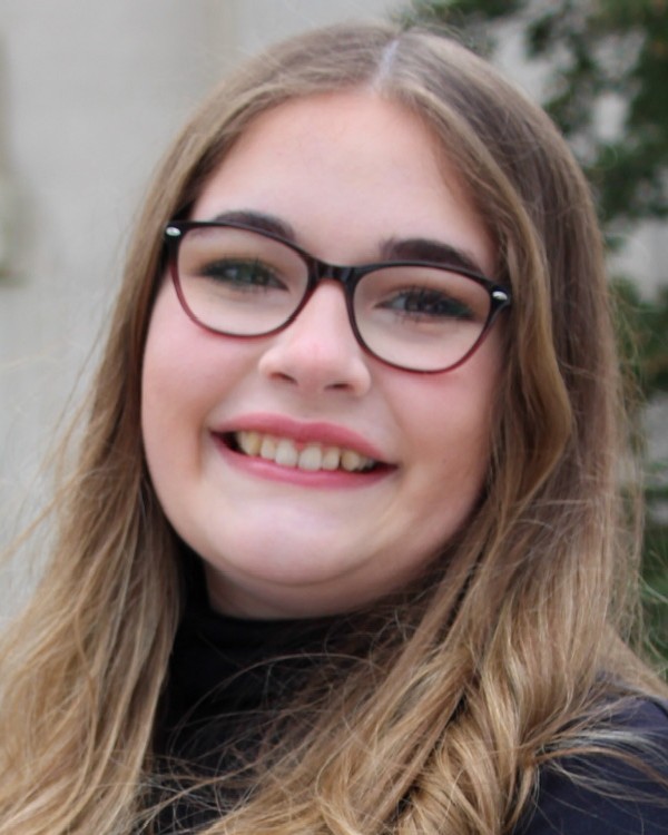 A picture of a person with blond hair and glasses smiling